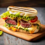 Das Chivito ist ein herzhaftes Sandwich, das mit einem Steak, Käse, Tomaten, Salat, Zwiebeln, Ei und Speck belegt wird. Das Steak ist saftig und knusprig, der Käse schmilzt im Mund und die anderen Zutaten sorgen für einen frischen und ausgewogenen Geschmack.